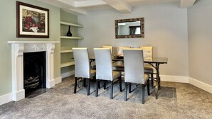 A dining area with a fireplace, a dining table with chairs, and a mirror on the wall.