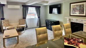 A living room with a fireplace, a TV mounted on the wall, and a dining area with a glass table.