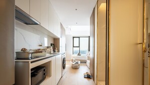 A modern kitchen with a built-in oven, microwave, and a small dining area with a table and chairs. - Vue Aston Condominium by Soben Homes (Phnom Penh)