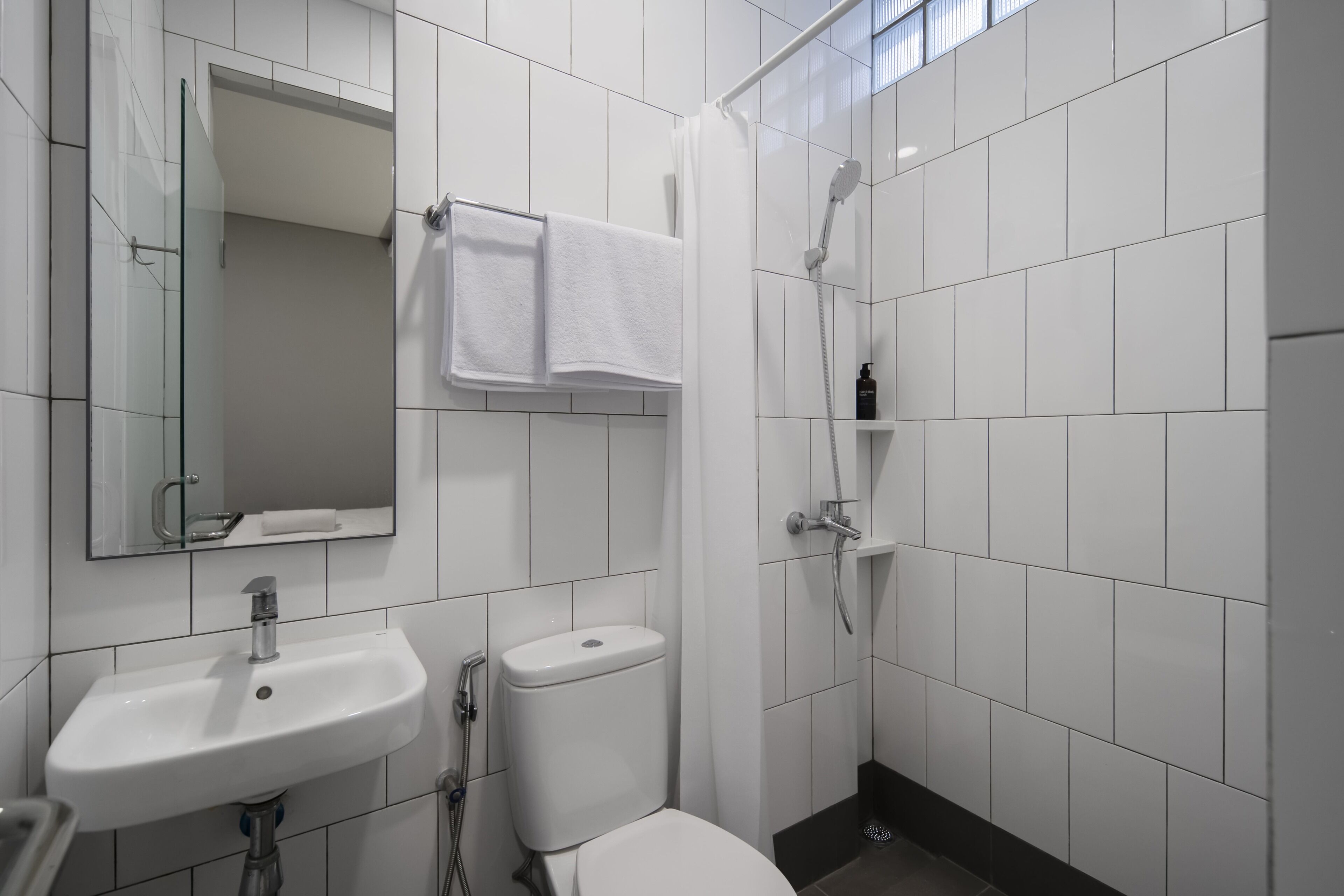 A bathroom with a sink, toilet, shower, and a mirror.