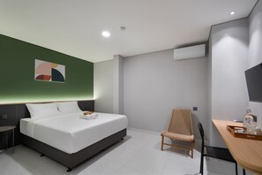 A modern hotel room with a bed, a chair, a desk, and a wall-mounted air conditioner. - Cove Vaia (Bandung)