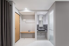 A modern bathroom with a wooden door, a bench, a mirror, and a sink. - Cove Vaia (Bandung)