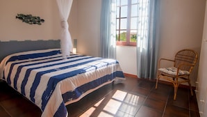 Une chambre à coucher avec un lit, une chaise, une fenêtre avec des rideaux et un élément décoratif mural.