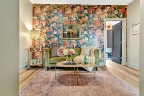 A living room with floral wallpaper, a green sofa, a coffee table, and a lamp.