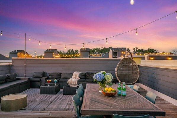 An outdoor seating area with a table, chairs, and string lights.