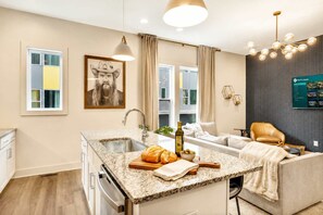A modern kitchen with a granite countertop, a built-in oven, and a dining area with a sofa and a coffee table. - Summer rooftop deck, 2-car garage, chef's kitchen near Broadway (Nashville)