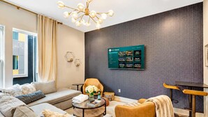 Een moderne woonkamer met een bank, fauteuil, salontafel en een aan de muur bevestigde televisie waarop een menu wordt getoond.