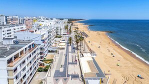 A coastal cityscape with a beach, buildings, and a clear sky.