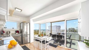 A modern apartment with a kitchen, dining area, and balcony with city views.