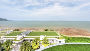 A modern hotel with a rooftop pool, a large lawn, and a view of the sea. - Chill Beachfront Vibes with 3BR Ocean Views & Pool (Sattahip)