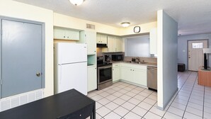 A kitchen with light green cabinets, a white refrigerator, a black microwave, and a stainless steel oven. - The Island Gem: Coastal Getaway (Corpus Christi)