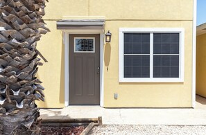 A yellow building with a gray door and a window.