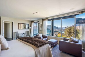 Habitación de hotel con una cama grande, dos sofás, una mesita y vistas a montañas.