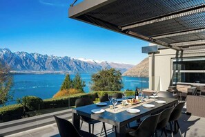 A dining area with a table set for four, overlooking a lake and mountains.