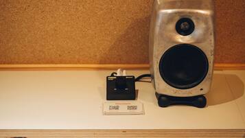 Un altavoz y una tarjeta con una lista de reproducción musical sobre una mesa.