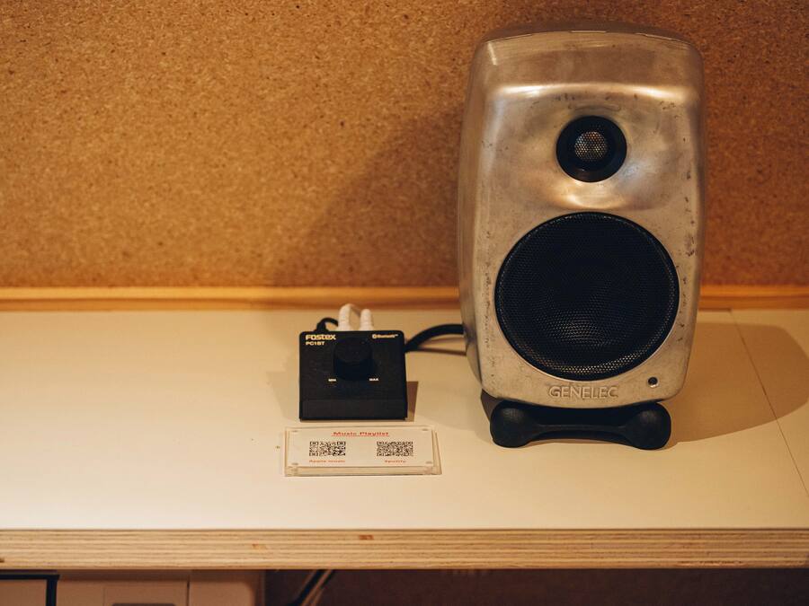 Un altavoz y una tarjeta con una lista de reproducción musical sobre una mesa.