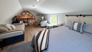 Ein Schlafzimmer mit einem großen Bett, einem Sofa, einem Schreibtisch und einem Erkerbereich mit einer Wendeltreppe.