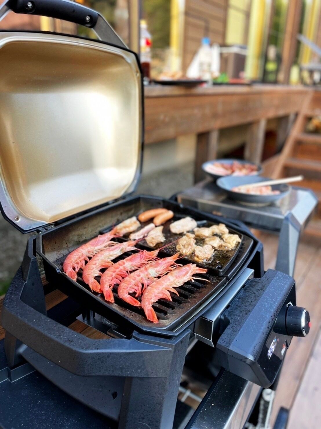 A portable grill with shrimp and vegetables being cooked.