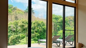 Un dormitorio con un ventanal grande que da a una terraza con sillones de descanso.