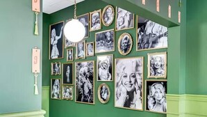 A room with green walls, a bench, and a wall decorated with framed pictures.