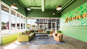 A modern lounge area with green walls, large windows, and a casual seating arrangement.