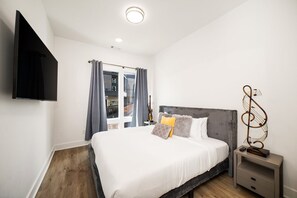 A bedroom with a bed, bedside table, and a wall-mounted TV. - Good Vibes on Main | A+ Location | 1 mi to DTNash (Nashville)