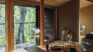 Een modern interieur met een groot raam, houten vloeren en een eethoek met een tafel gedekt voor twee personen.