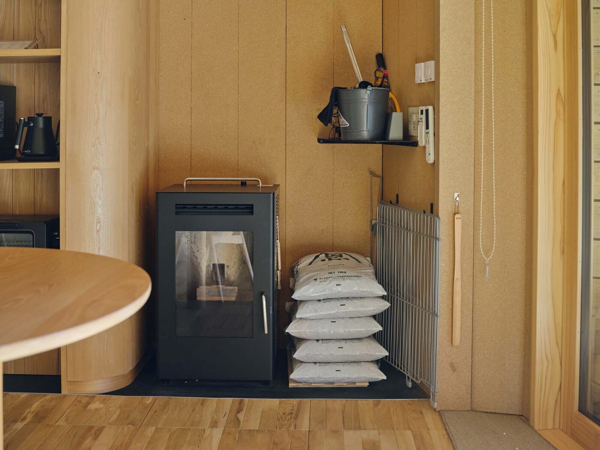 Una cocina compacta con estufa integrada, un estante pequeño con utensilios de cocina y un radiador.