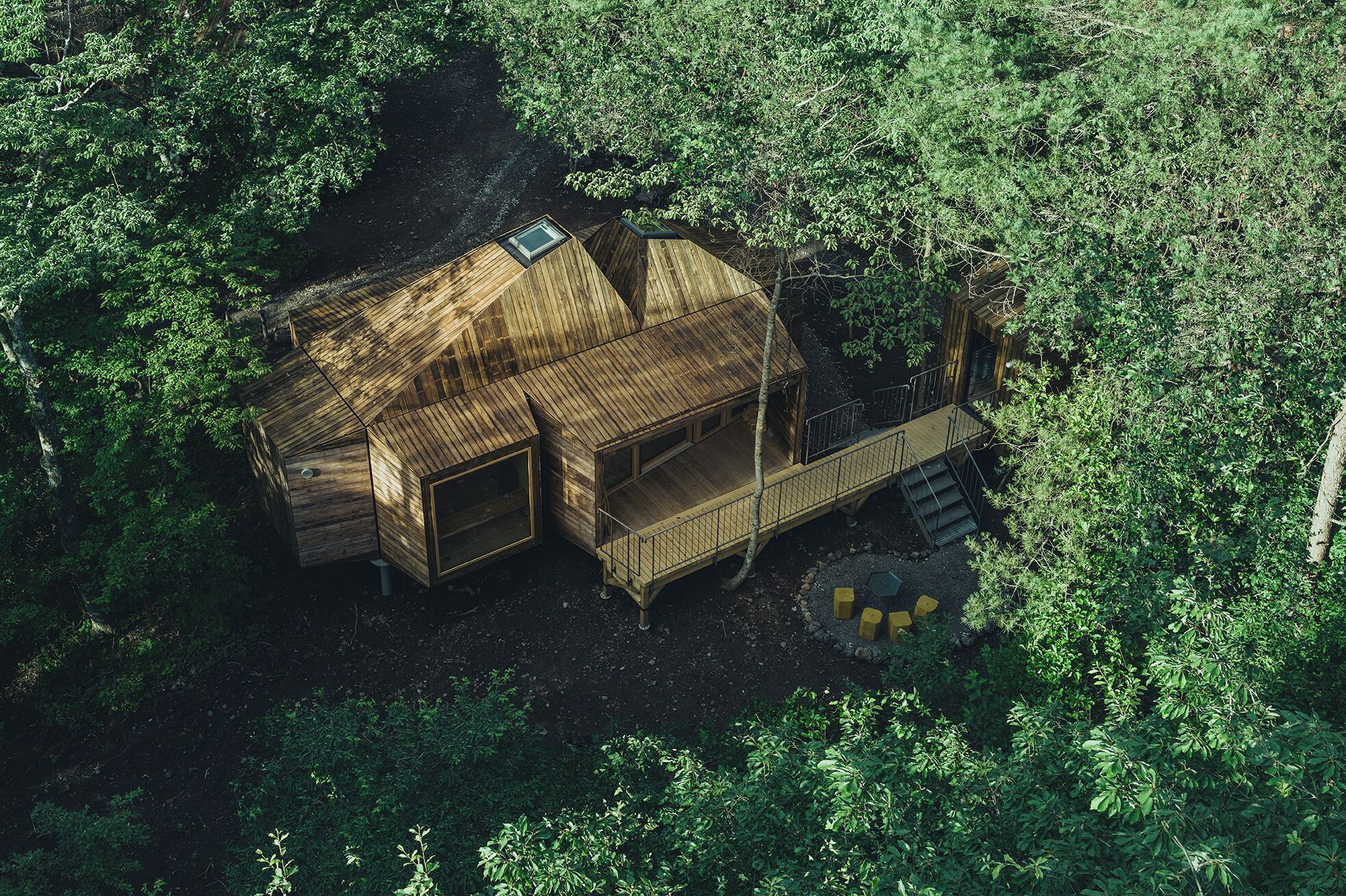 A wooden cabin with a sloped roof, a balcony, and a staircase leading to a deck.