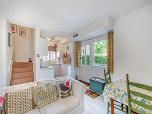 Una sala de estar acogedora con sofá, una mesa de comedor y una zona de cocina.