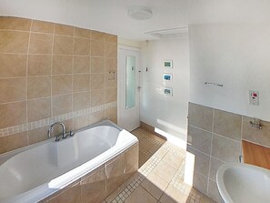 Een badkamer met een bad, toilet en douche.