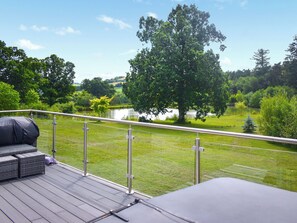 Une terrasse dotée de mobilier d’extérieur, offrant une vue sur un lac et des arbres.