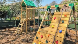 A wooden playground structure with a climbing wall and a slide. - 3 bedroom accommodation in Sidmouth (Sidmouth)
