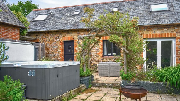 A brick house with a tiled patio, a hot tub, and a barbecue grill. - 3 bedroom accommodation in Sidmouth (Sidmouth)
