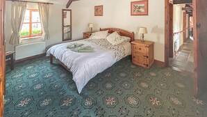 A bedroom with a large bed, two bedside tables, a mirror, and a window with curtains.