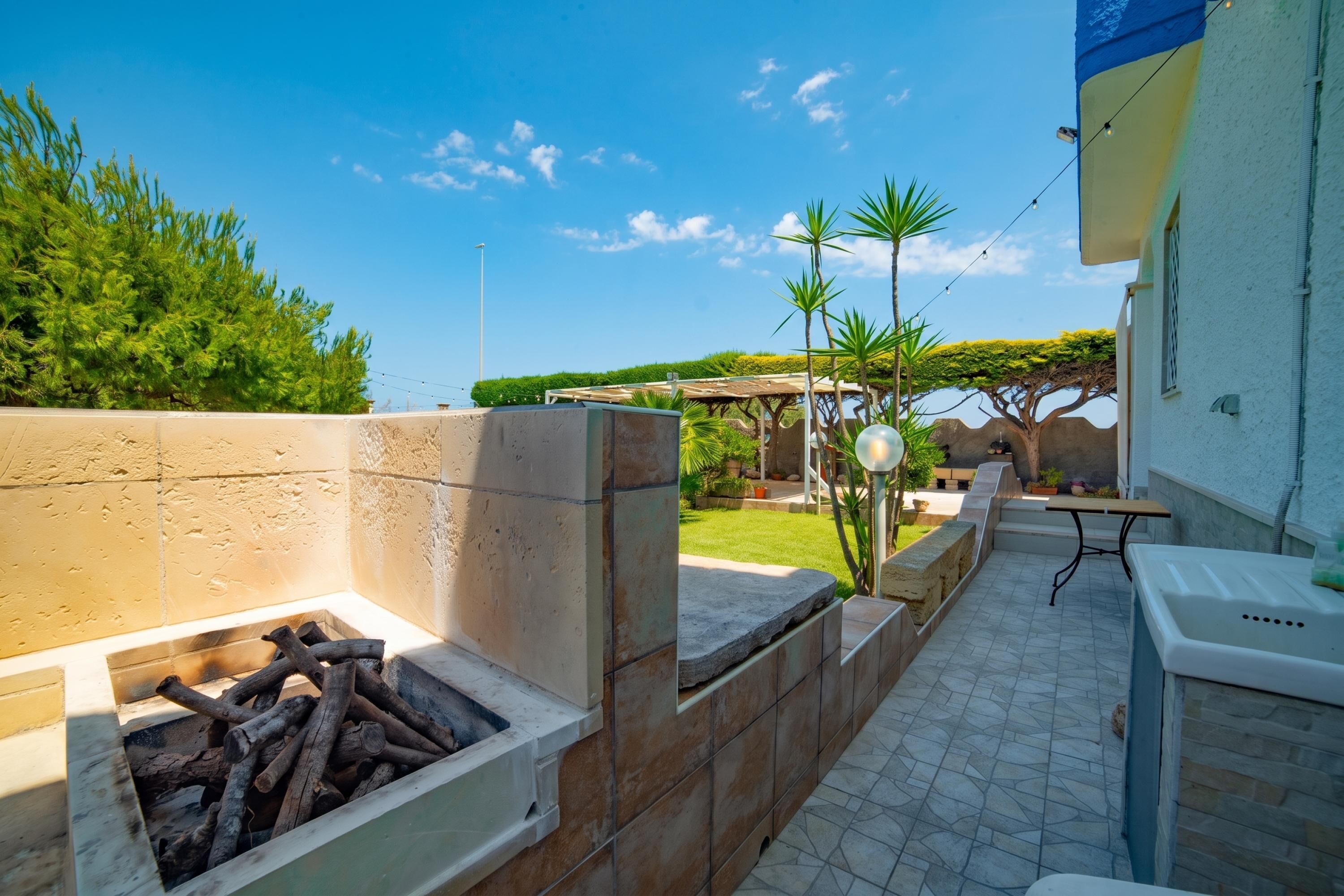 Uma área de pátio com lareira, mobiliário de exterior e vista para o jardim.