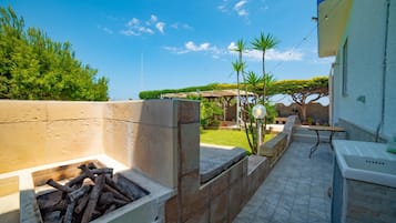 Uma área de pátio com lareira, mobiliário de exterior e vista para o jardim.