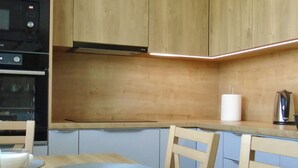 Una cucina moderna con mobili in legno, forno integrato e tavolo da pranzo con sottopiatti.