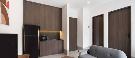 A modern living room with a grey sofa, a wooden coffee table, and a black TV stand.