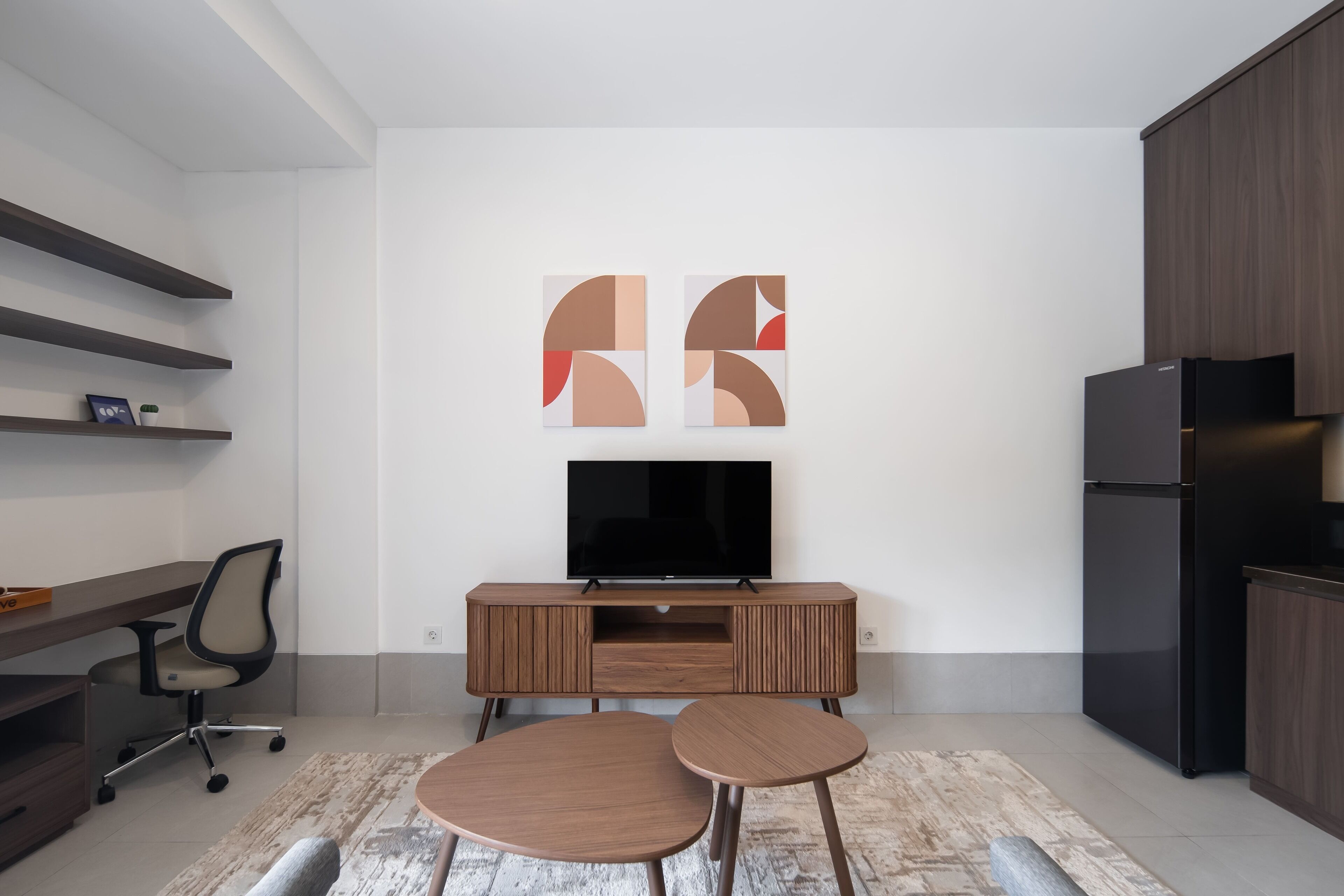 A modern kitchen with a built-in TV, wooden cabinets, and a dining area with two stools.