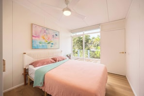 A bedroom with a bed, a ceiling fan, a window with a view, and a painting on the wall. - The Art House Designed by Kirsten Jackson (Blairgowrie)