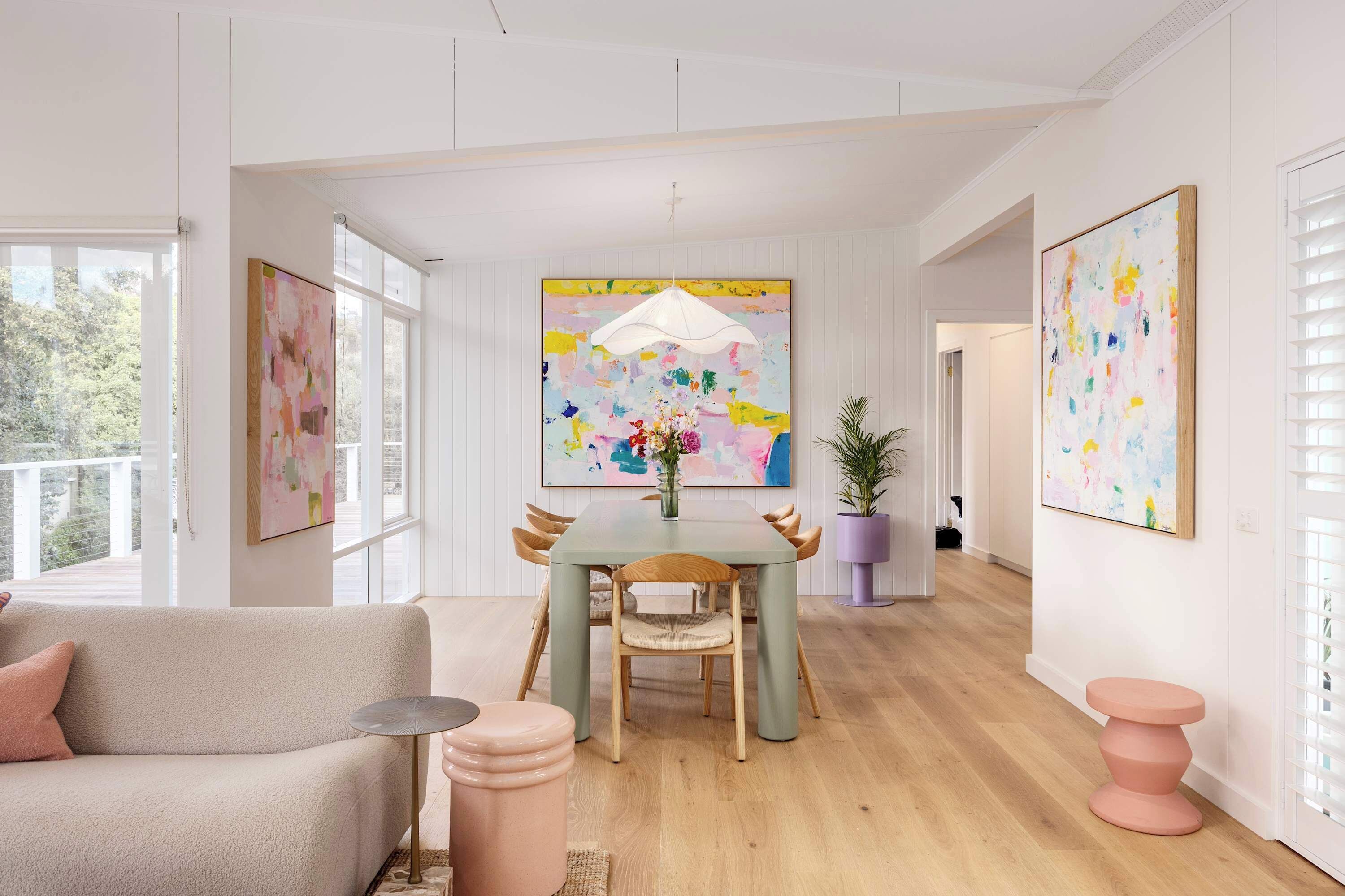 A modern living room with a sofa, a dining table with chairs, and artwork on the walls.