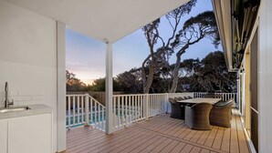 A wooden deck with a pool, outdoor furniture, and a view of trees. - Saltwood Coastal Hamptons Luxe with Pool (Rye)