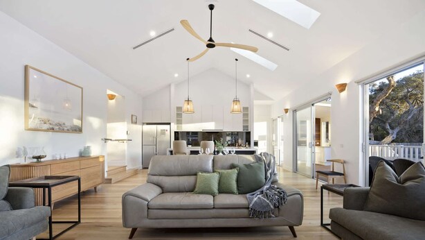 A spacious living area with a modern sofa, a dining table, and a kitchen in the background. - Saltwood Coastal Hamptons Luxe with Pool (Rye)