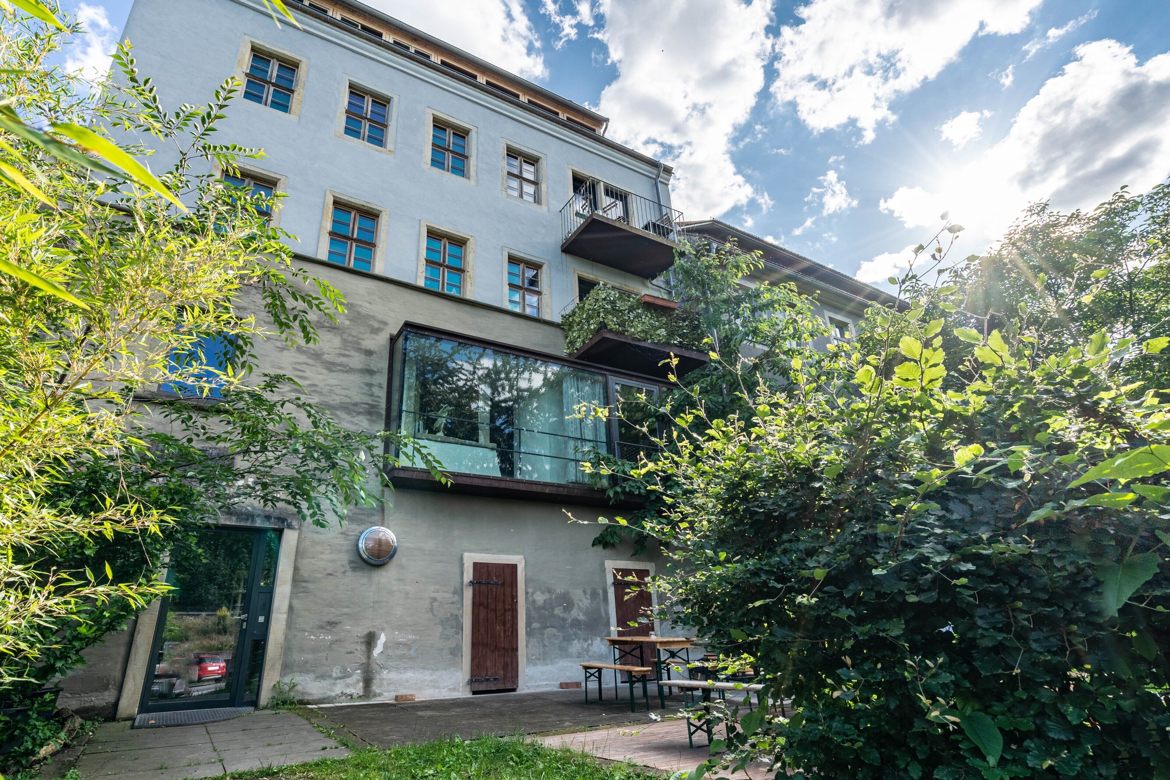 Ein Gebäude mit großem Glasfenster, einer Tür und einer kleinen Außenbestuhlung.