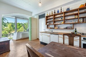Eine Küche mit Holzausstattung, einer Arbeitsplatte und einem Fenster mit Blick auf Grünflächen.