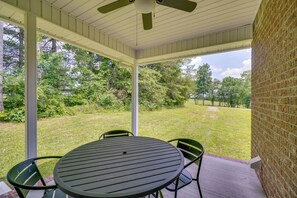 Une terrasse couverte avec une table et des chaises, un ventilateur de plafond et un mur en briques.