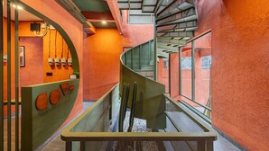 A modern interior with a curved staircase, a reception area with a unique design, and a view through a glass partition. - Cove The Cave (Denpasar)
