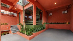 A modern building with a red exterior, a staircase leading to a green platform, and a flat roof. - Cove The Cave (Denpasar)
