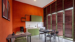 A modern kitchen with green cabinets, a white countertop, and a dining area with a table and chairs. - Cove The Cave (Denpasar)